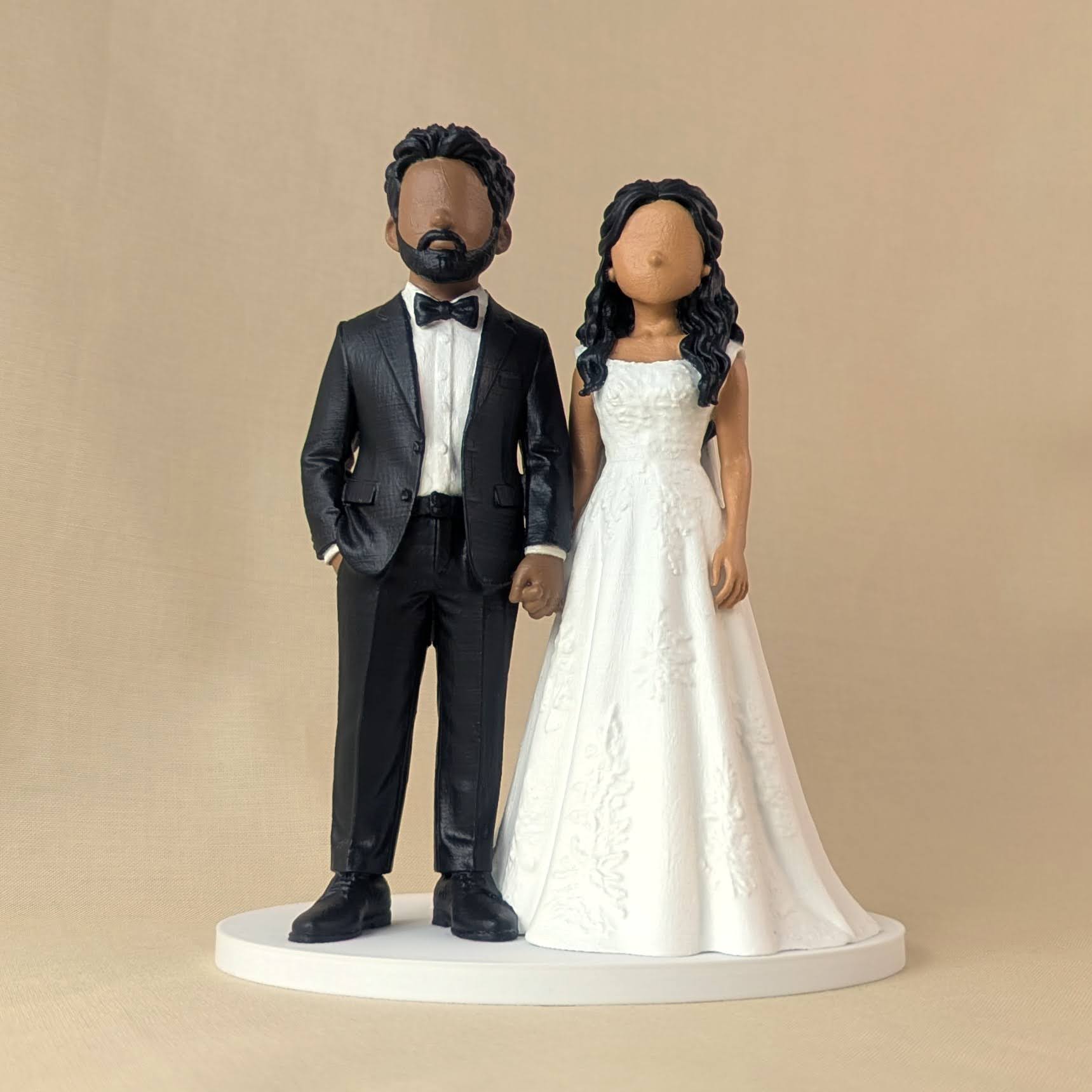Custom wedding cake topper of a bride and groom holding hands, groom in a black tuxedo and bride in a lace A-line gown